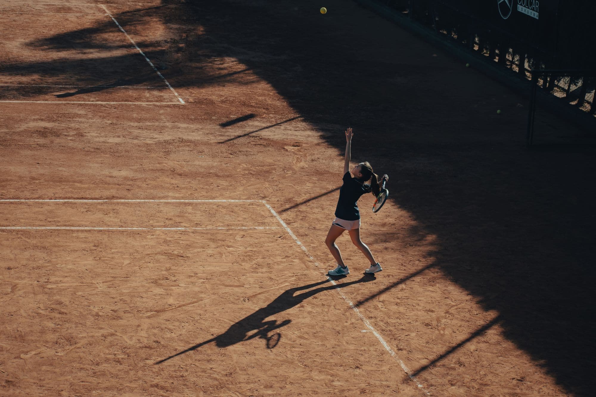 Aerial view of a clay tennis court in late sun