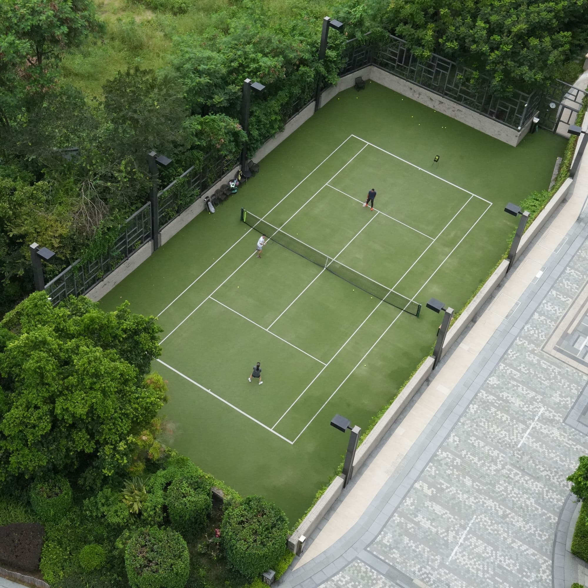 Aerial view of a club tennis court surrounded by greenery