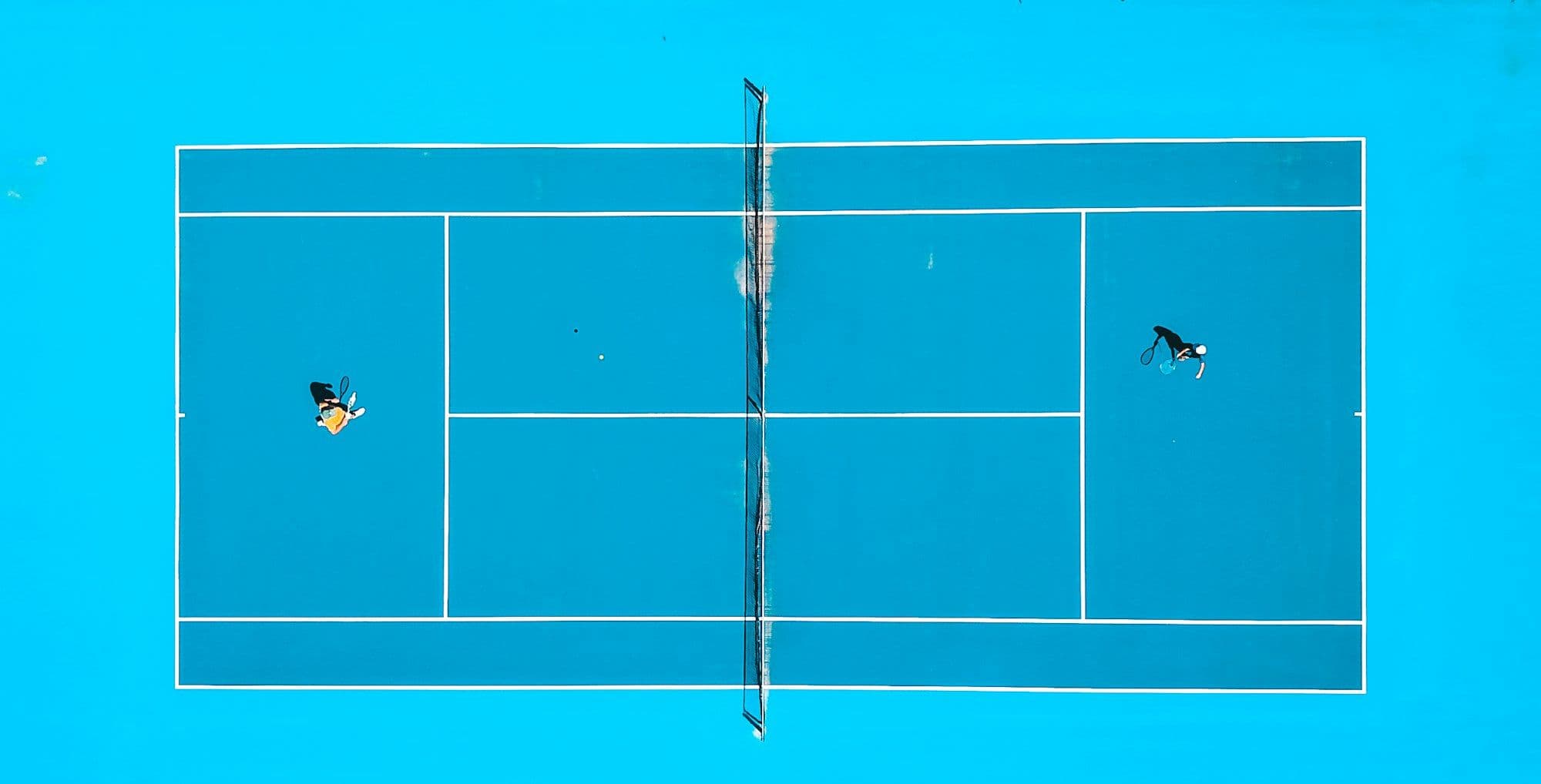 Top-down view of a doubles match on a cyan court