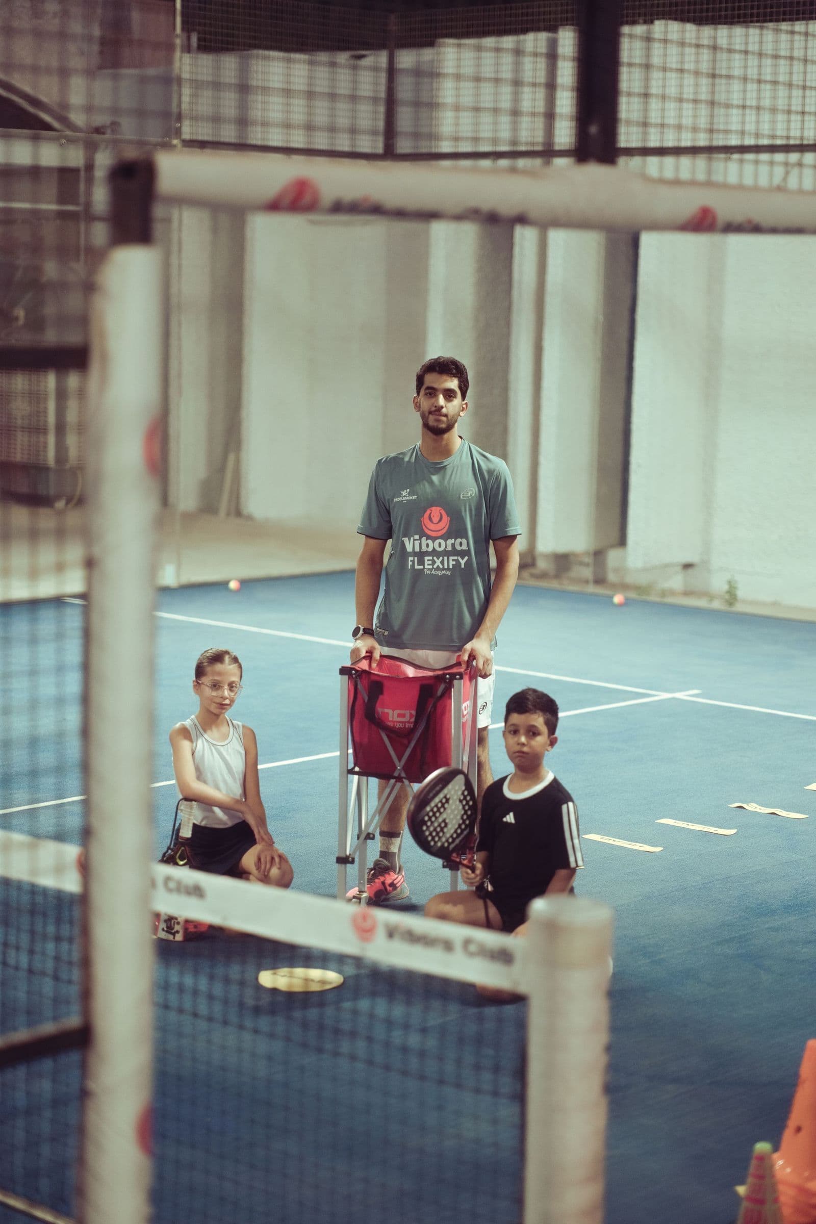 A coach with two young players and a ball cart