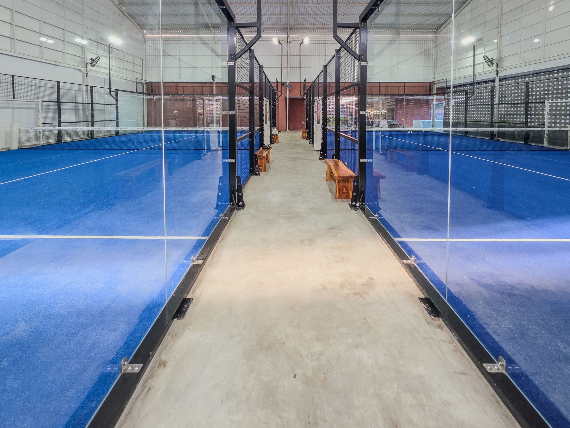 A walkway between two indoor padel courts
