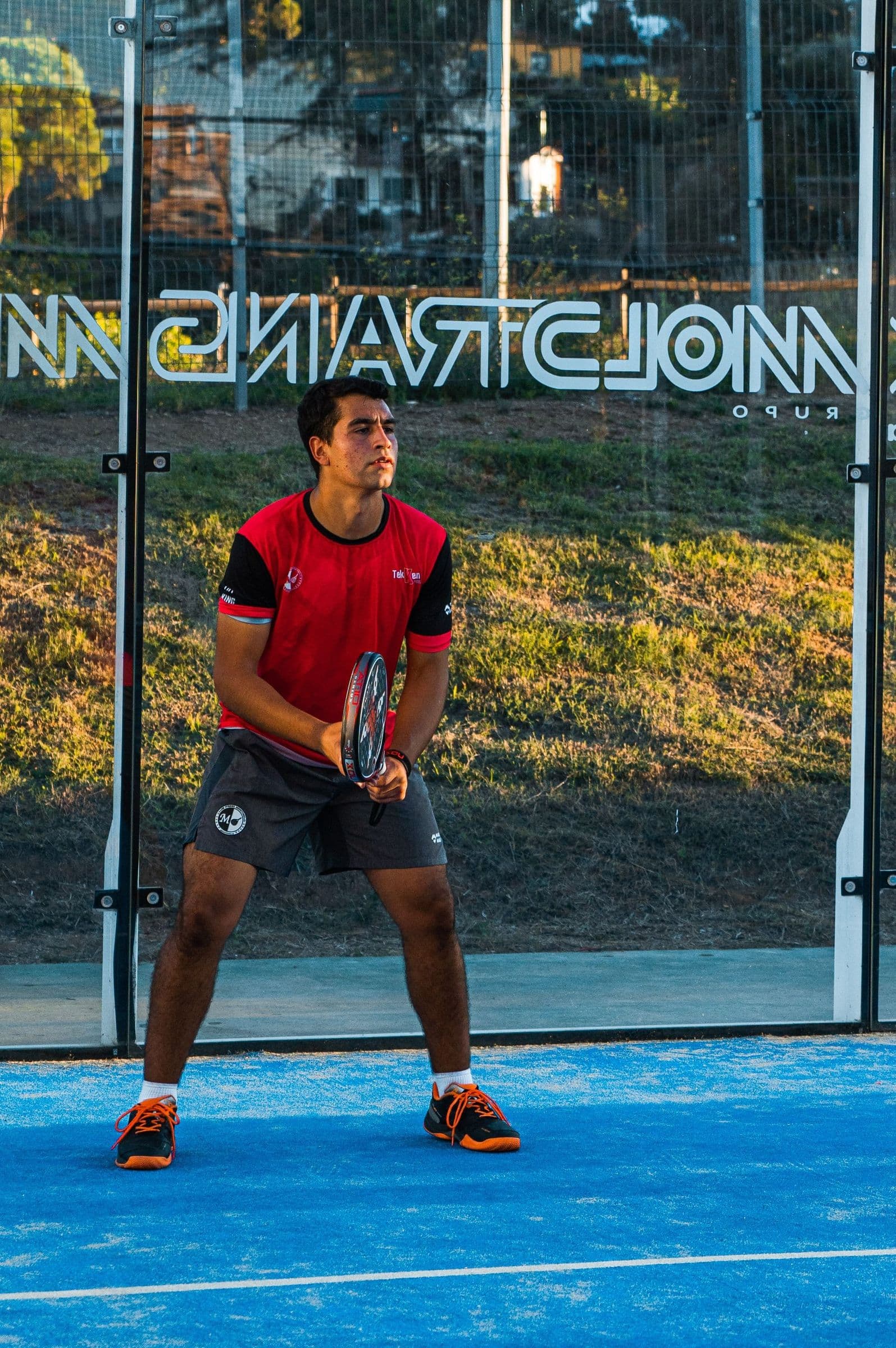 A padel player ready at the net on a blue court