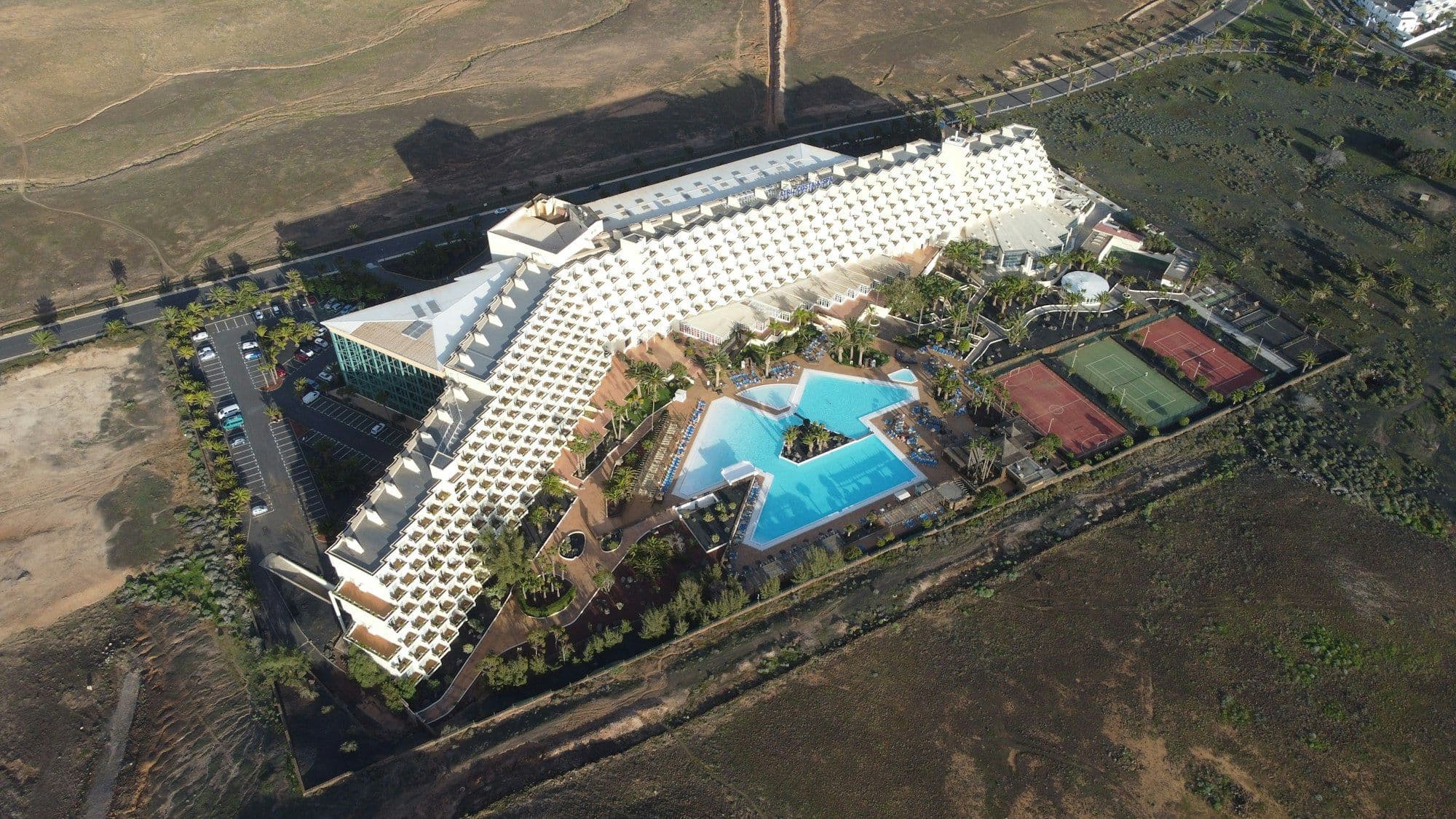 Aerial view of a beach resort with pools and tennis courts