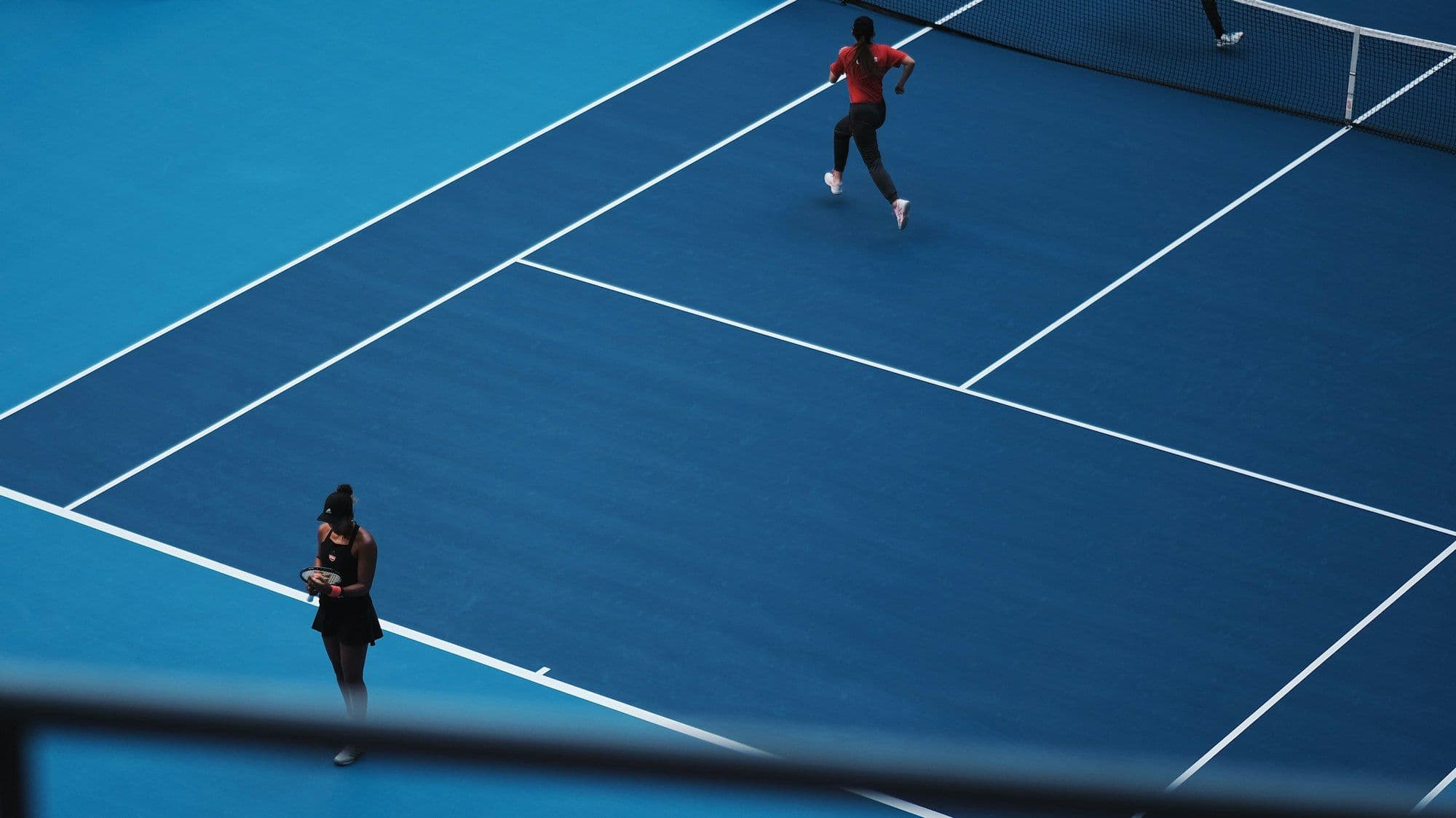 Two players on a blue tennis court, seen from above