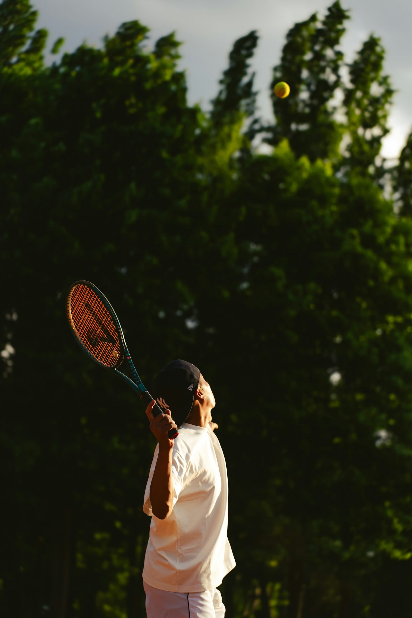 A tennis player serving in golden evening light