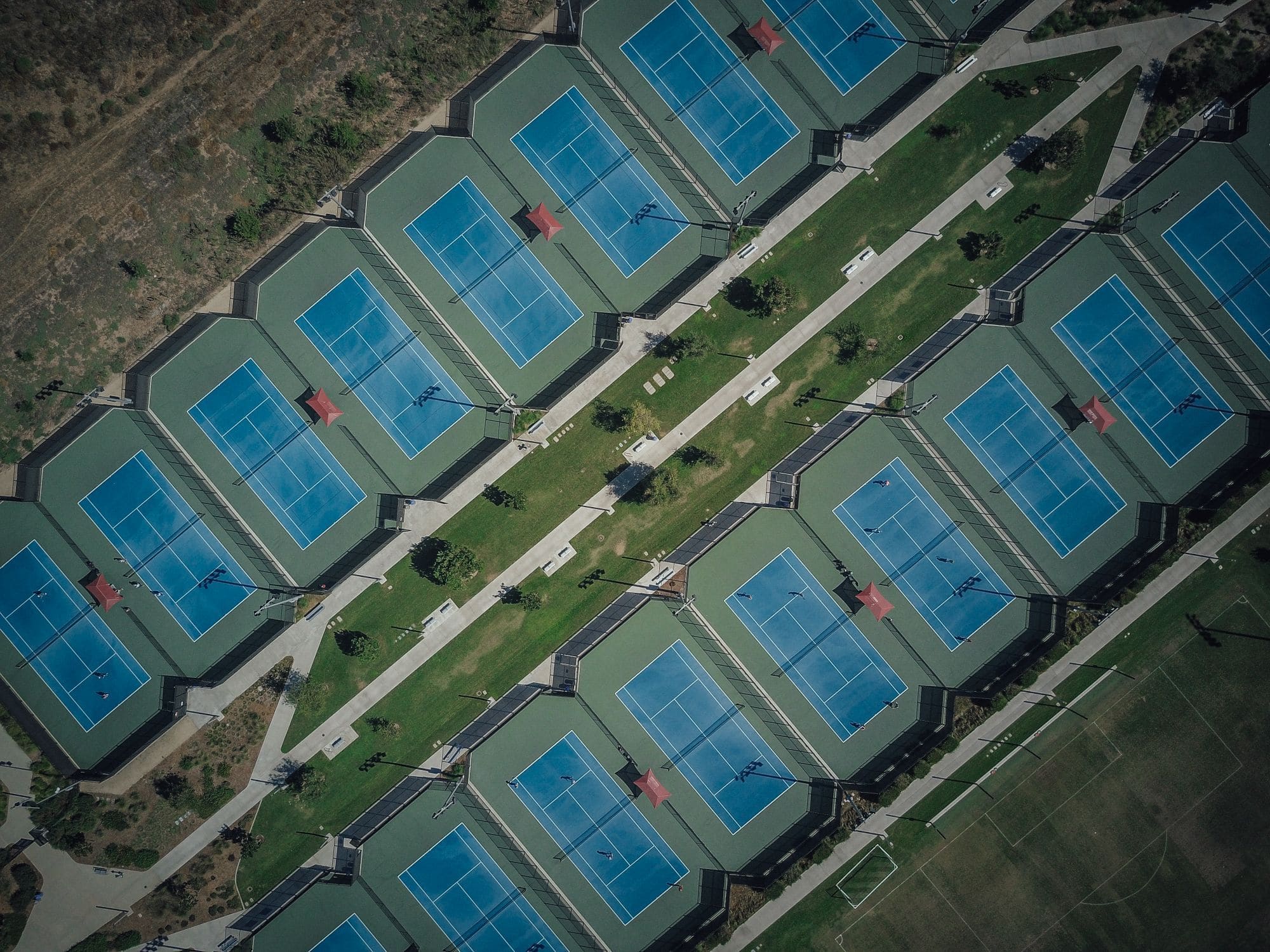 Aerial view of rows of tennis courts beside a park