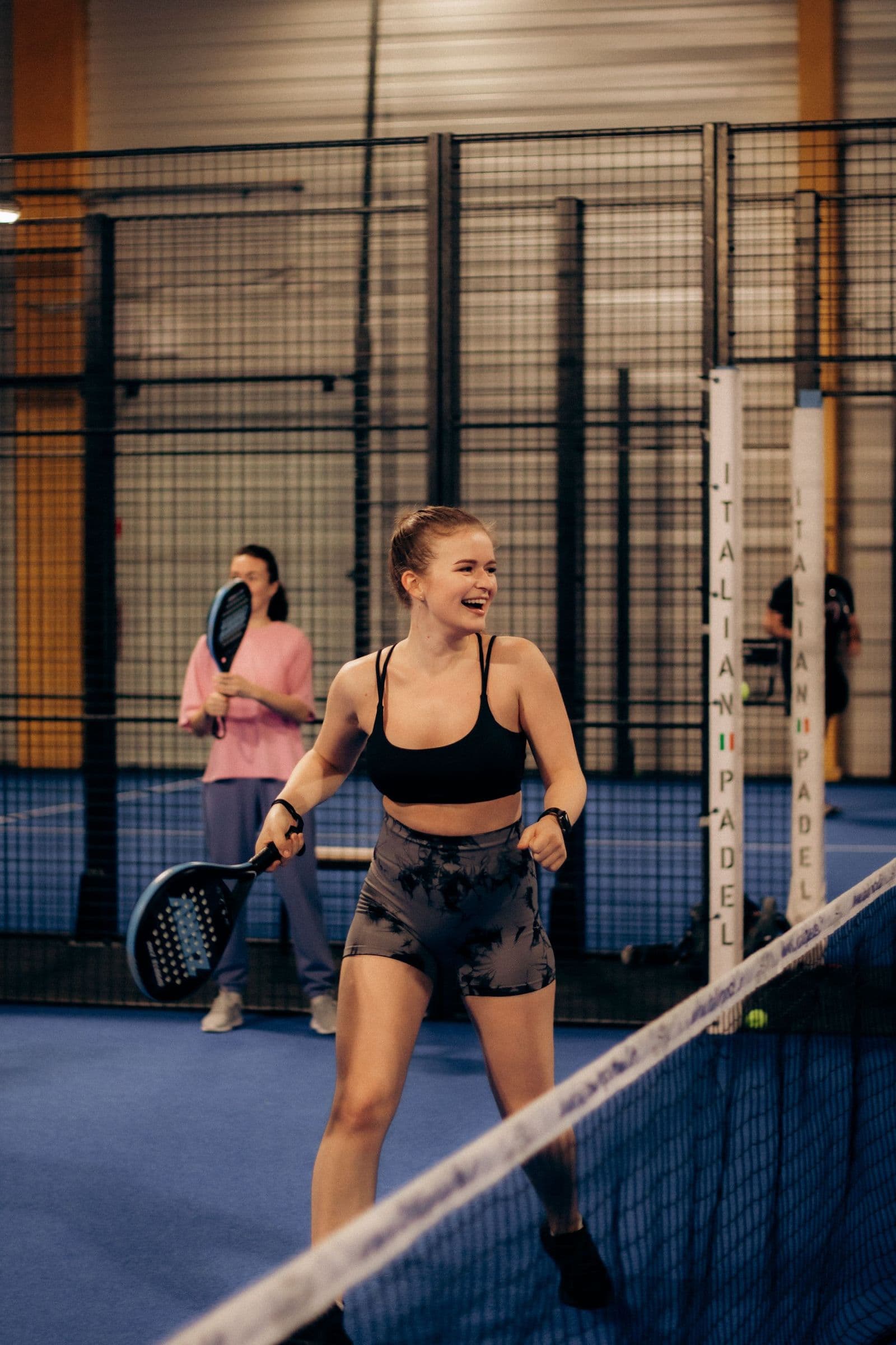 Two beginners rallying on an indoor padel court