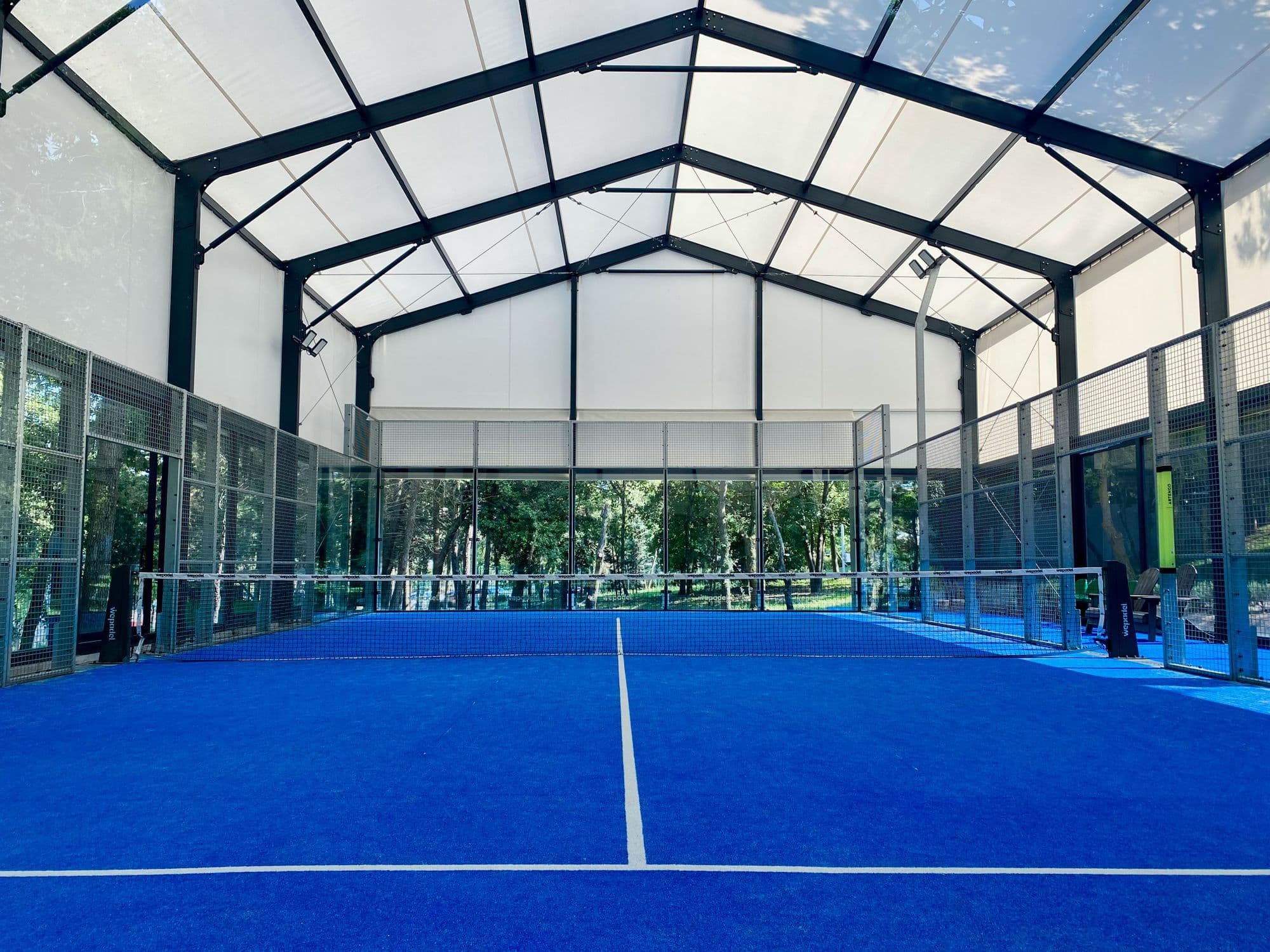 A large indoor padel hall with blue courts