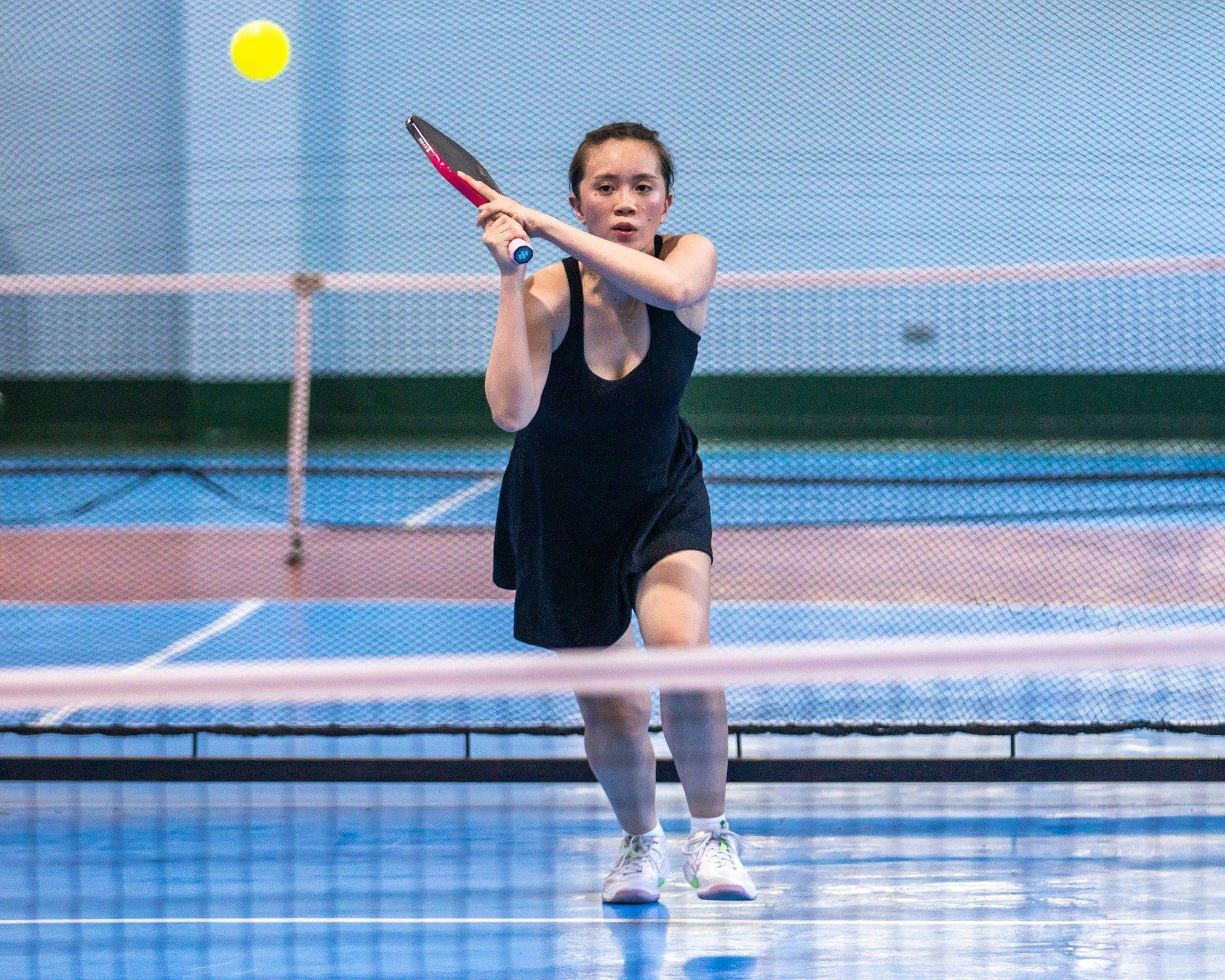 An indoor blue tennis court under roof lighting
